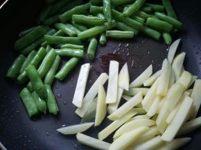 炒至四季豆断生，皮皱起。放入土豆条炒至断生。