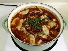 鱼煮好后，将干料包、干辣椒和葱撒在鱼表面上。
