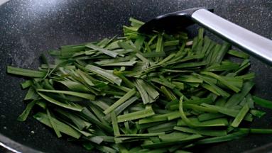 锅中留底油倒入韭菜进行翻炒。