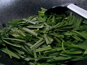 锅中留底油倒入韭菜进行翻炒。