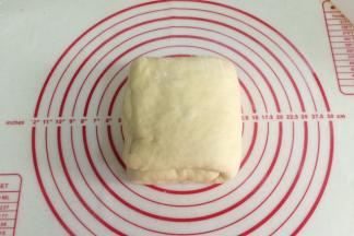 然后把折叠好的面团换个方向，用擀面杖慢慢的擀开。