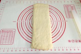 上下两侧分别向中间1/3处折叠，顺着上下方向擀长。