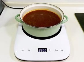 往汤锅内倒入适量的清水，把翻炒过的调料酱加入锅内煮开。