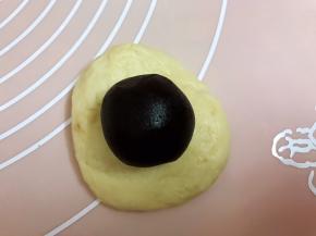 取一份面团排气擀开包入一个红豆沙，收口滚圆