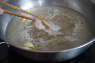 锅里的水烧开后，放入姜、蒜、花生油，加入瘦肉片