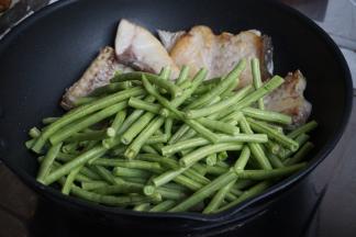 豆角倒入，将豆角翻至锅底，鱼肉放豆角上面。加入适量水、酱油、一丁点糖、一匙蚝油、盐（盐不要放太多，因为鱼肉已经用盐腌过）