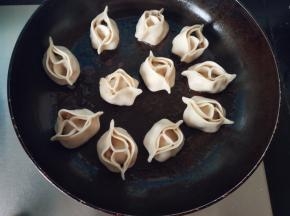 等锅里的水份收得差不多了，掀开锅盖转大火，淋一勺油再煎一分钟让饺子底部再脆！关火，撒上葱花和熟黑芝麻就可以装盘了！