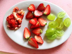 草莓一部分中间对半切开，一部分切碎，绿提子对半切开