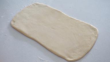 取出冷冻好的面团，操作台撒粉防粘，擀成豆沙的两倍大小