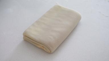 再将面团对折 完成一次四折
然后包裹住保鲜袋 继续冷冻松弛10分钟