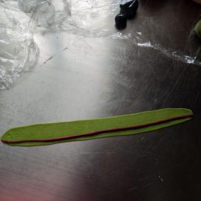 用同样的方法来做青蛙的脸颊，取一个红色的面团搓长，取一个18克的绿色面团擀长包裹住红色的面团，做好两个保鲜膜盖好备用