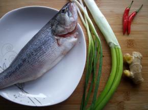 鲈鱼去腮去内脏，洗净备用。准备大葱，小葱，两个小米椒和一块生姜。