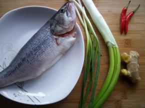 鲈鱼去腮去内脏，洗净备用。准备大葱，小葱，两个小米椒和一块生姜。