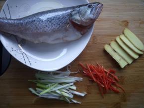 鲈鱼抹少量盐，淋上料酒，腌制15分钟，上蒸锅前淋少量的油。姜切片，小米椒去籽切丝，大葱切丝。