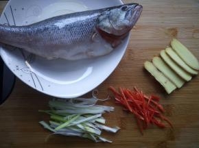 鲈鱼抹少量盐，淋上料酒，腌制15分钟，上蒸锅前淋少量的油。姜切片，小米椒去籽切丝，大葱切丝。
