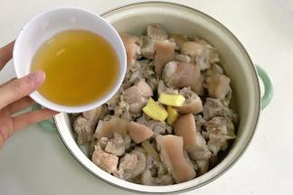 往猪蹄内放入姜片，倒入180克的料酒。