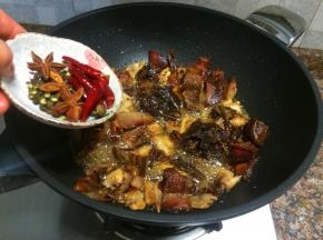 放入花椒、八角和干红辣椒翻炒10秒。