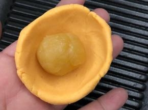 红薯皮涅成圆形包入绿豆沙馅料搓圆。