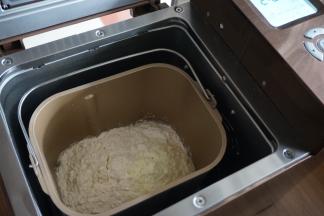 将酵母水倒入面包桶中，加入面粉和奶粉，面包桶放入面包机里