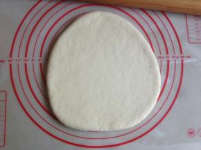 面团发酵好后，揉一揉，用擀面棍将面团擀平，看见有气泡就捏破它