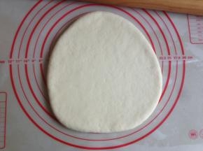 面团发酵好后，揉一揉，用擀面棍将面团擀平，看见有气泡就捏破它