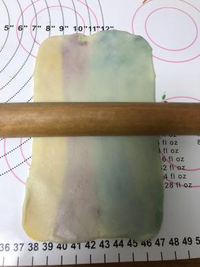 轻轻擀长，注意不要擀破，每个颜色要均匀宽度，把左右边多出来的白色面团切掉