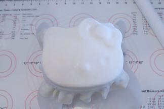 蛋糕体表面刷一层薄薄的镜面果胶，覆盖好糖皮，按KT的脸部轻压好眼睛、鼻子、蝴蝶结