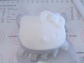 蛋糕体表面刷一层薄薄的镜面果胶，覆盖好糖皮，按KT的脸部轻压好眼睛、鼻子、蝴蝶结
