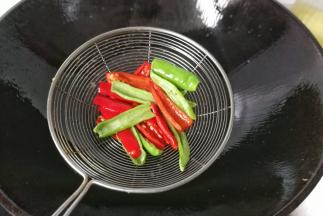 再把青红辣椒条也放入油中，过下油后迅速捞起