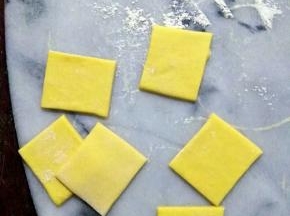 南瓜面团静置好后，排气，擀成薄片。
切成4*4cm的小方片 