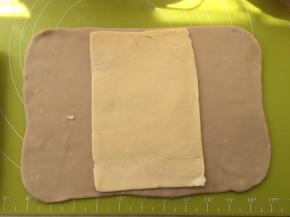 冰箱取出冷冻的面片跟黄油，用剪刀将包裹黄油的保鲜袋裁开，将黄油片铺在面片中间