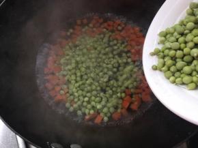 锅烧开水放入胡萝卜丁煮开后加入豌豆米