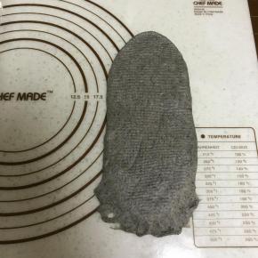 松弛好的面团从中间向两侧擀成牛舌状，从一侧卷起。