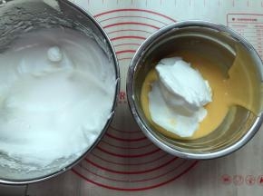 将1/2的蛋白霜倒入蛋黄糊中，用手动打蛋器从盆底由下向上快速翻拌