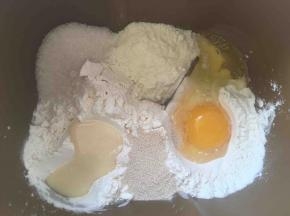 面包桶内加入高筋面粉，低筋面粉，奶粉，酵母，鸡蛋，细砂糖跟酵母