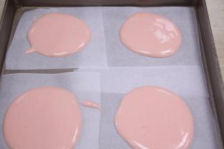 加入一滴粉红色素，把面糊调成粉红色，用裱花袋装上面糊，挤出螺旋形在烤盘上。