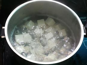 锅中加水约1000ml，放入姜丝烧开后加入豆腐和白贝，煮至白贝开壳