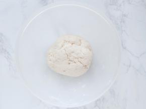 用筷子把面粉搅成小疙瘩，再用手慢慢拢成一个面团。此时面团是比较柔软的。