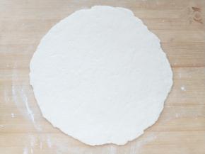 操作台上撒干面粉，把面团表面也均匀粘满面粉，擀成和烤盘差不多大小的面饼。