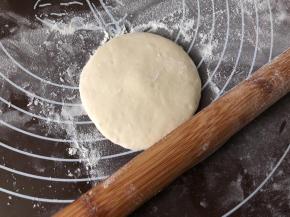 把小面团按扁，擀成中间厚四周薄的圆片。