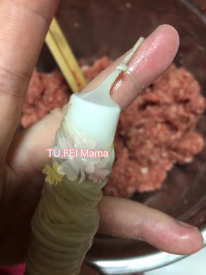 12. 肠衣套好后，肉馅灌在灌肠器里。然后拧的时候把肉馅顶到马上就要出来的位置停止，把肠衣顶部打个结。之后就可以继续灌了。灌的时候注意［用手控制肠衣的长短，肠衣的顶部每次都跟肉馅的出口处有点距离，这样防止灌肠中用力过猛在肉馅出口处炸开］灌好的部位可以用牙签适当扎几个小洞，不要扎太多太密，适当，也可以防止炸开。还能帮助排出因为自己灌肠不熟练灌进去的空气。