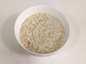把60克的即食燕麦片放入碗内，倒入200克开水拌匀，放凉备用。