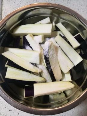 茄子洗净，去蒂，切成和手指差不多粗的长条，撒上适量食盐腌制十几分钟。