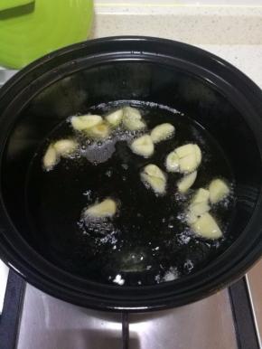 砂锅洗净，开大火烧干水分，倒入适量食用油，茄子是需要油多才能好吃的菜，稍微比平时做菜多放些油。放入切碎的大蒜，爆香。