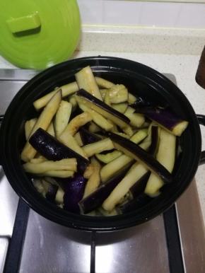 腌过的茄子用手掐出水分，茄子全部倒入砂锅中，翻拌一下。