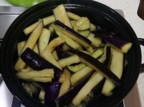 腌过的茄子用手掐出水分，茄子全部倒入砂锅中，翻拌一下。