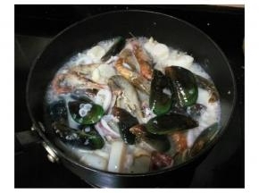 将所有海鮮放入锅里炒，倒入白酒、蒜盐和什錦香草碎，待青口开口将海鮮倒入盘里备用（炒海鮮时会溢出的汤汁不要倒，一会要倒入米里烩）