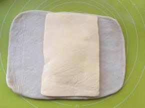 取出冷冻的黄油片，用剪刀裁开保鲜袋，将黄油片铺在面片中间