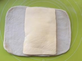 取出冷冻的黄油片，用剪刀裁开保鲜袋，将黄油片铺在面片中间