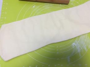 撒点干粉，用擀面杖将面片轻轻擀成长条，长度跟揉面垫的长度相近